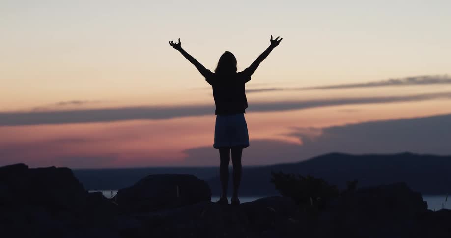 A woman is stretching outdoors at dusk