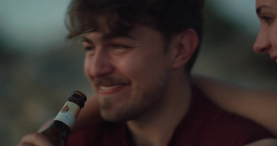 Man and woman are outdoors drinking a beer together