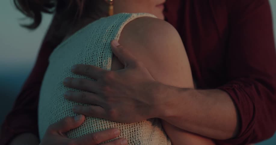 A man and woman are standing together hugging and they kiss