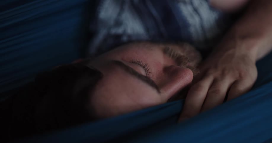 Man peacefully sleeping taking a nap on a blue hammock