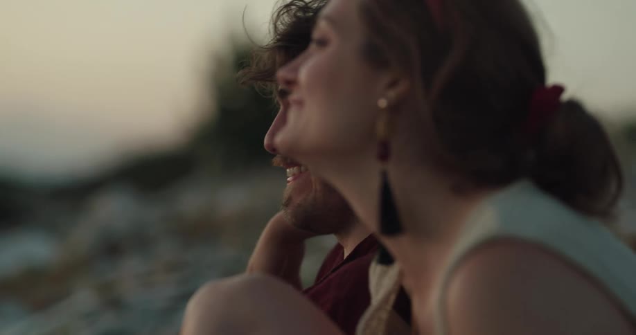 A man and woman sit together enjoying a beer and smiling