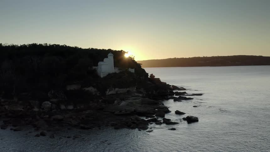 Sun rising and shining brightly over a rocky coastal area