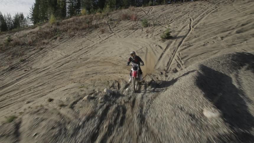 A person riding a motorcycle goes down a dirt track