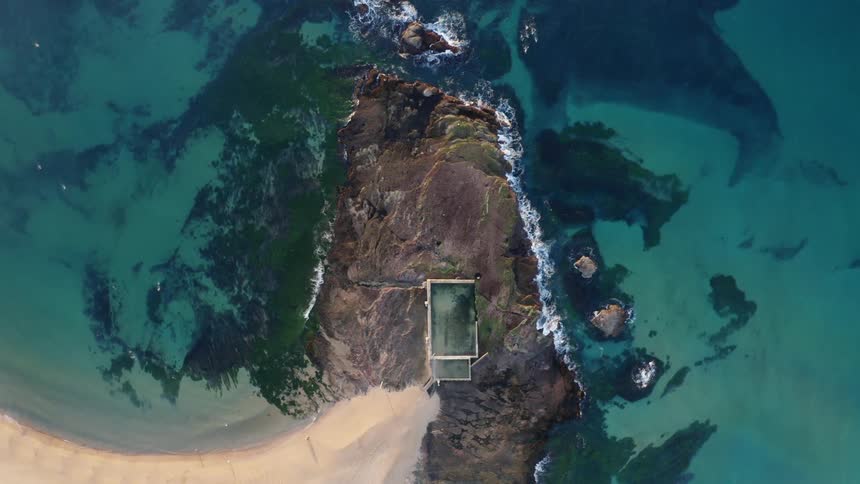 A building on a headland on the ocean coast during the day