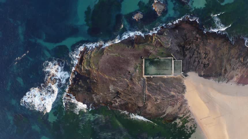 Aerial view of an island next to an ocean is displayed