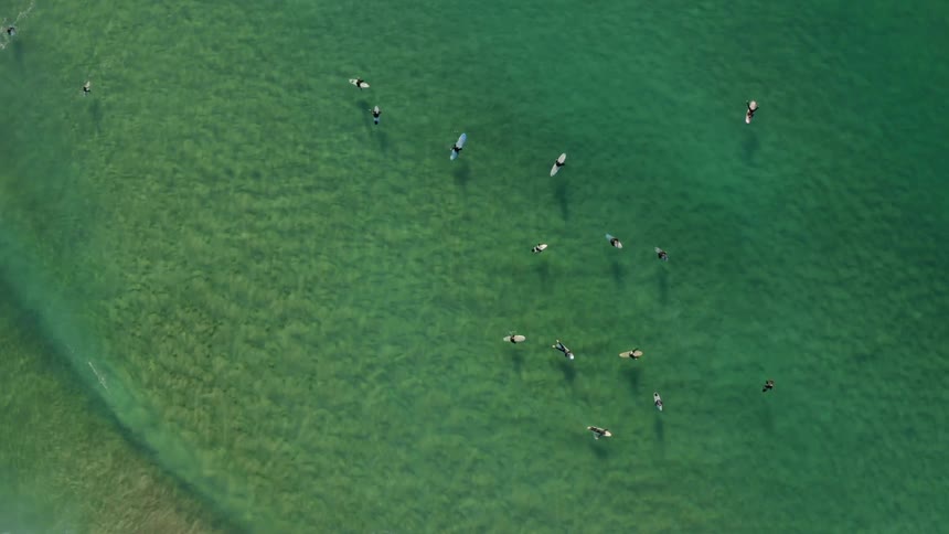 People floating on surfboards over the clear green ocean water