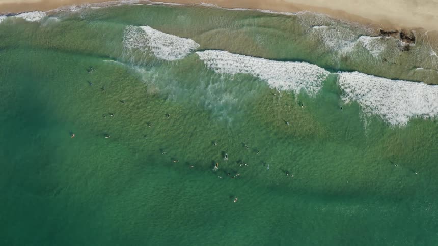Aerial view of the ocean waves moving towards the coast is displayed