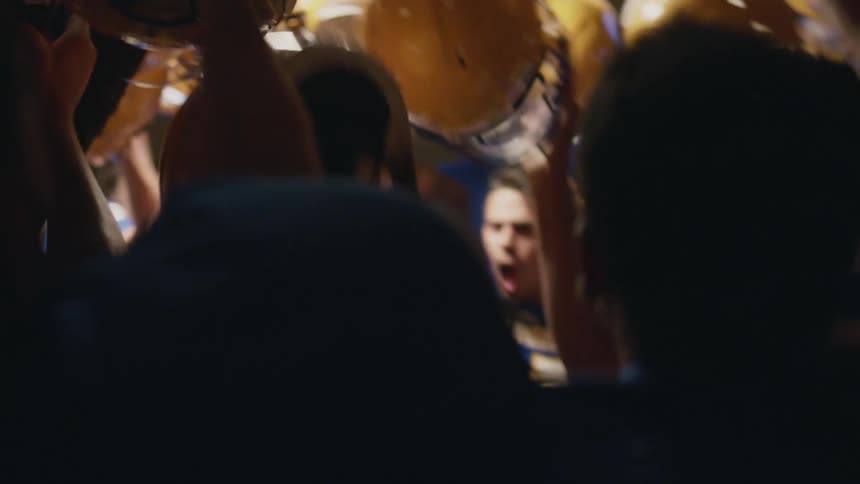 A group of football players celebrate in a locker room