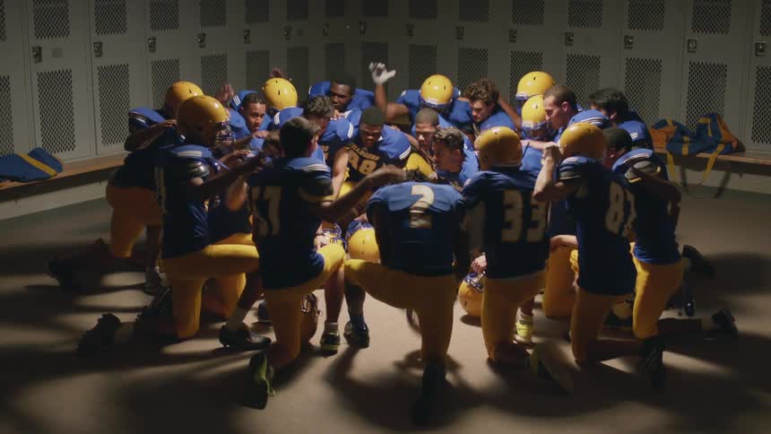 A bunch of football players in the locker room rallying for a game