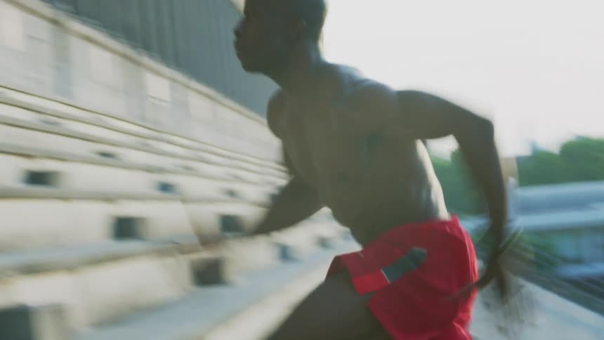 A shirtless man sprints up bleachers