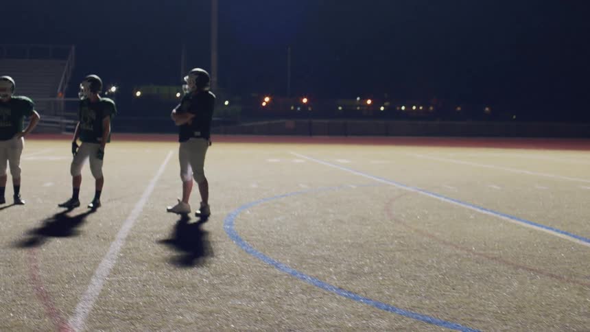 Group of men on a football field at night