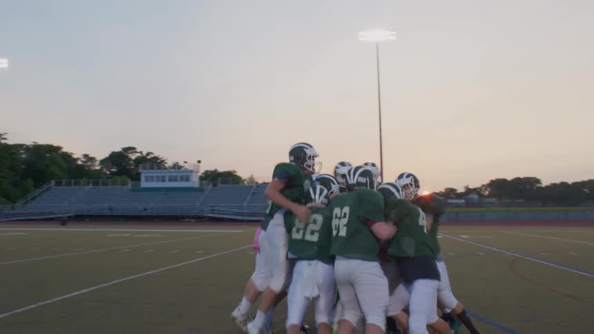 A group of football players embracing each other in a field