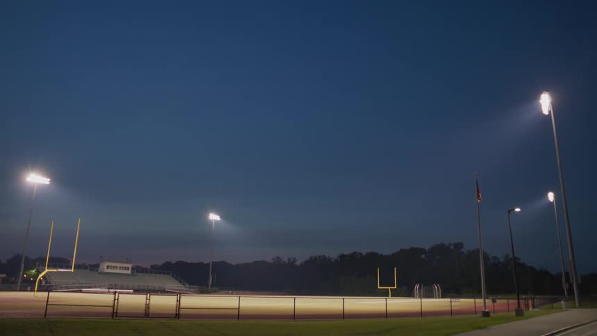 A view of a football field as the lights are turned of at dusk