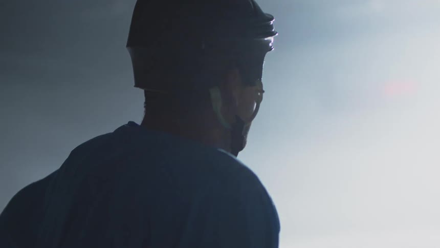 A hockey player is standing on the ice staring towards a light