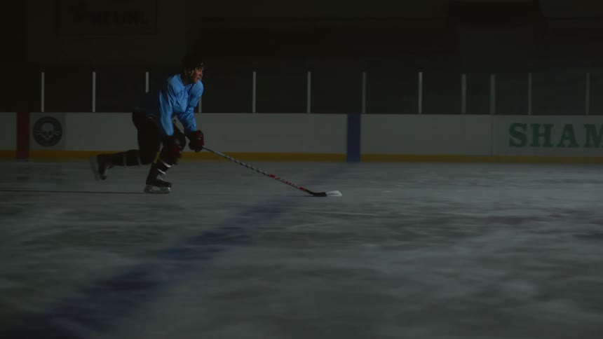 An ice hockey player practicing alone in a rink