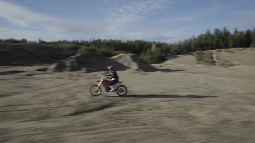 A motorbike drives fast down a dirt field