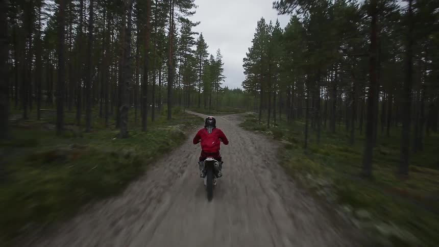 Traveling view behind a dirt bike speeding over a dirt trail