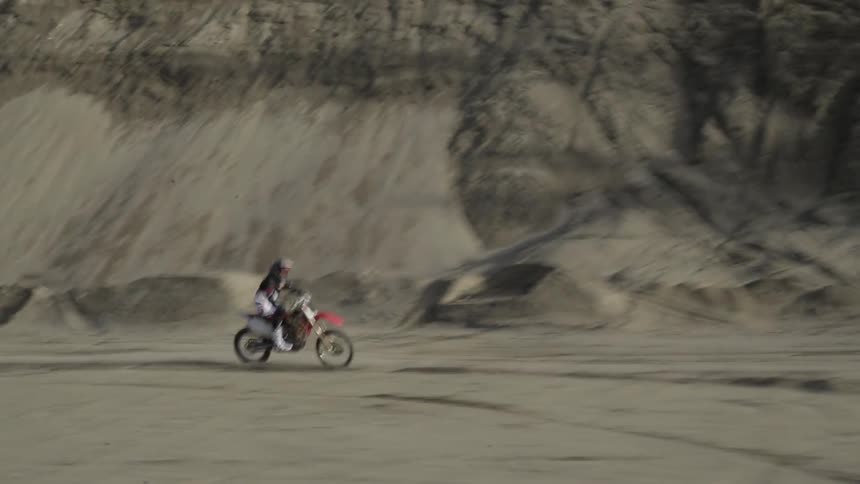 A man rides a motorcycle over dirt and gravel