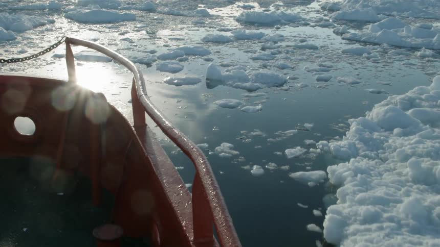 A boat is moving through the water with ice all over
