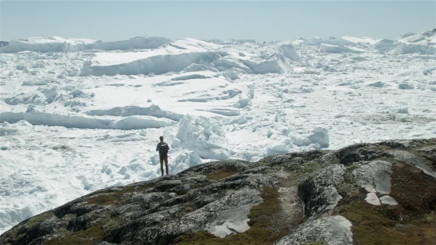 Man standing atop a mountain looking over some vast snowiness