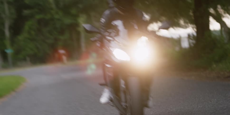 Motorcyclist with a black helmet and jacket rides motorcycle on the country road