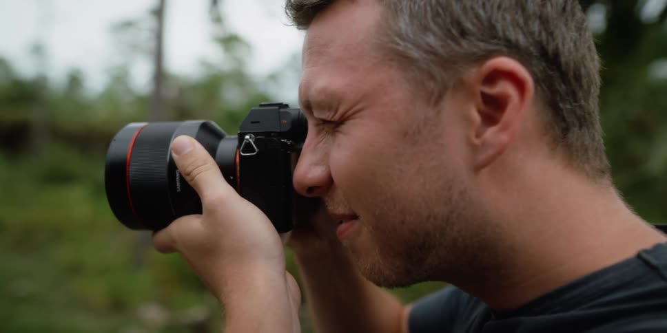 A man that is using a camera outdoors