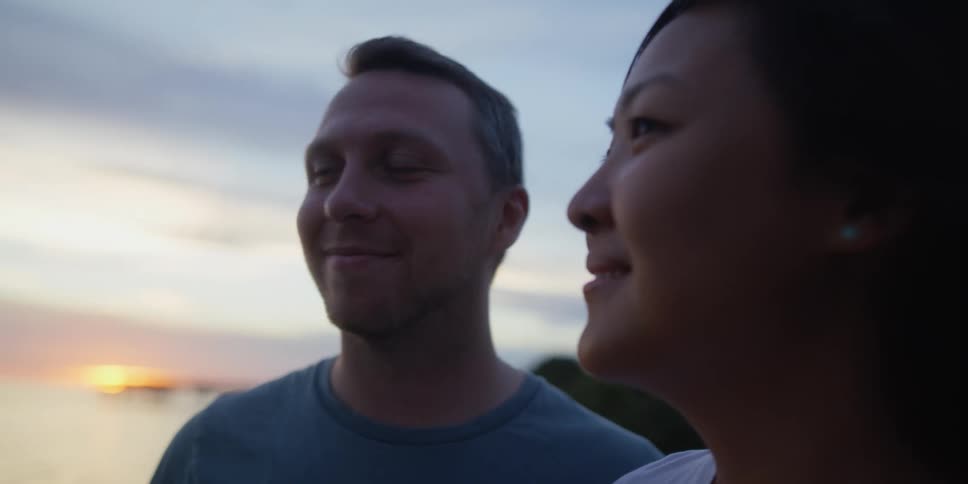 Man and woman look lovingly at each other while standing near a lake