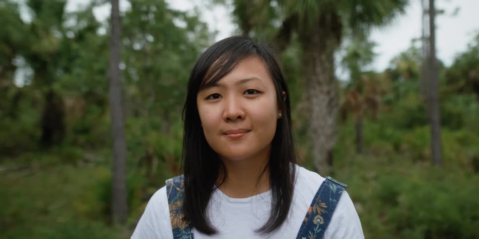 Woman is outdoors in a tropical area and smiling