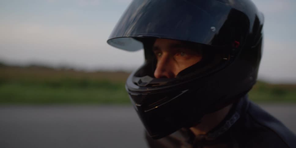 A man opens the visor on his motorcycle helmet