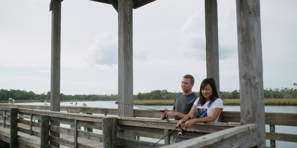 Man and woman are fishing together off a dock