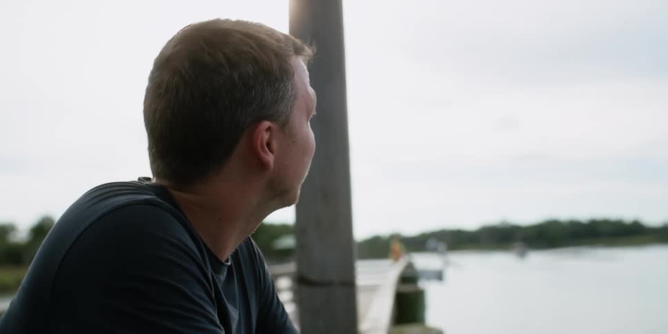 Man fishing while standing on a pier in the lake at daytime
