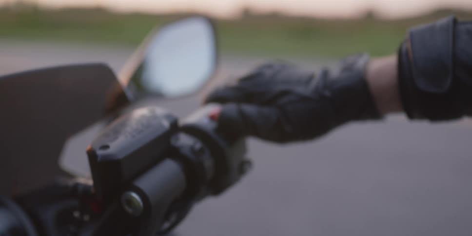 Motorcyclist wearing a black glove turns the key in the ignition then presses a button on the handlebar to start the motorcycle