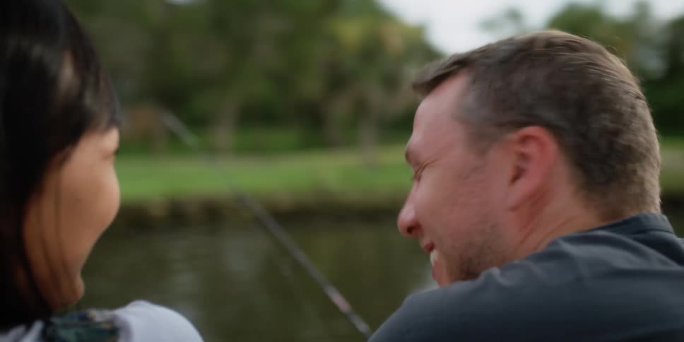 Man and woman smile and laugh while fishing in a lake