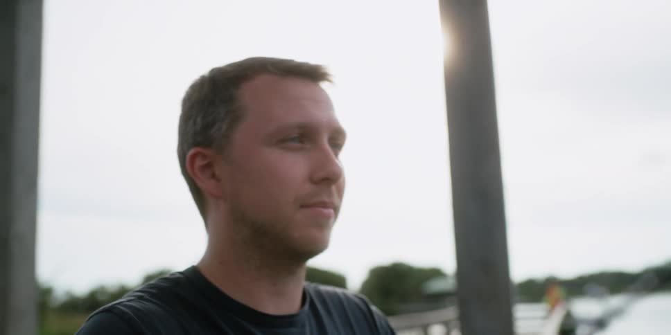 Man with a dark t shirt casts a fishing line on the coast