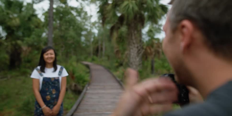 A man is taking pictures of a woman in a tropical area