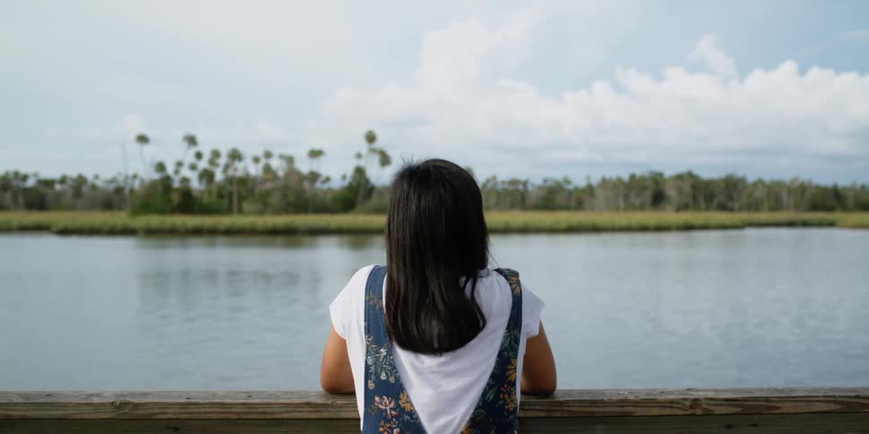 A woman is standing by a lake in spring