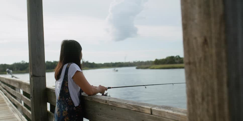 A woman is fishing on the pier