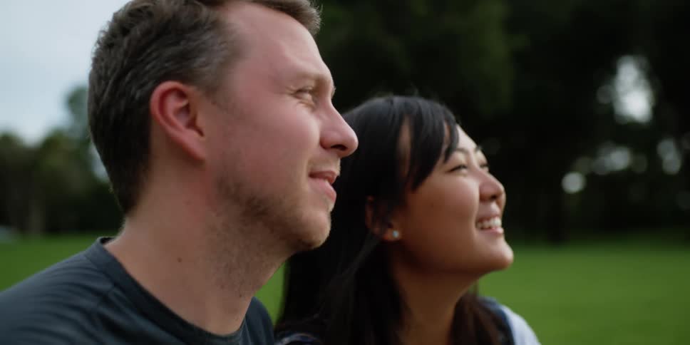 Man and woman are sitting in field and smiling