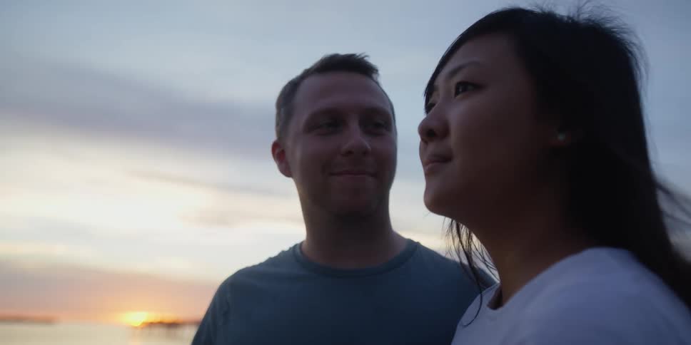 A man and woman stand together outside on a windy day