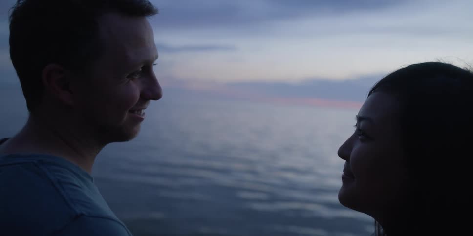 A couple face each other by the shore