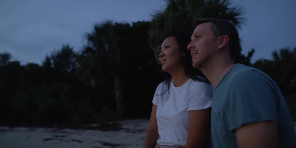 A man and woman are sitting on the beach together