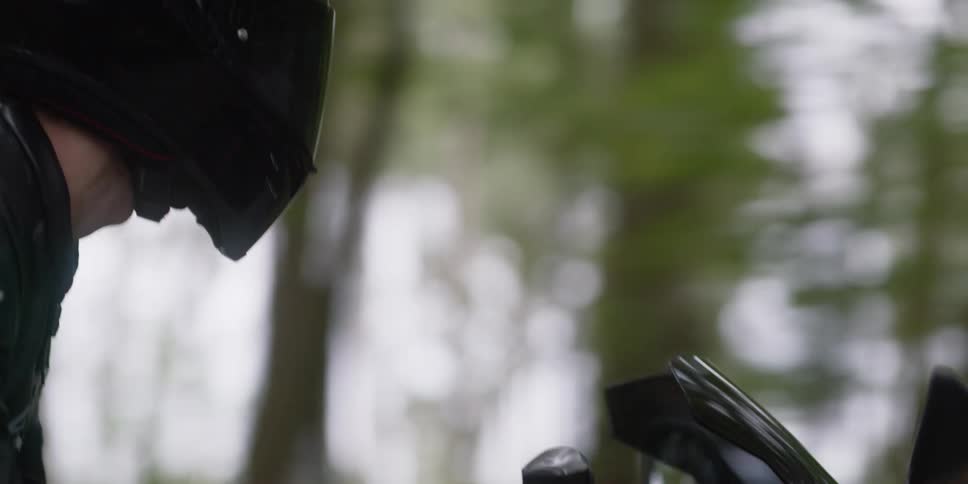 A person is riding a motorcycle on a treelined path
