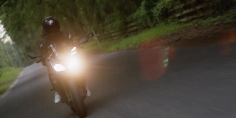 A motorcyclist rides down a narrow rural road