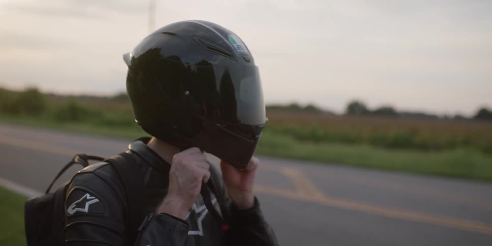 A man removing a helmet while sitting on a motorcycle
