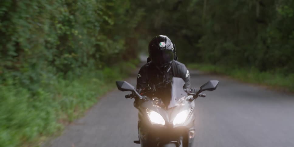 A person is riding a motorcycle down a road in spring