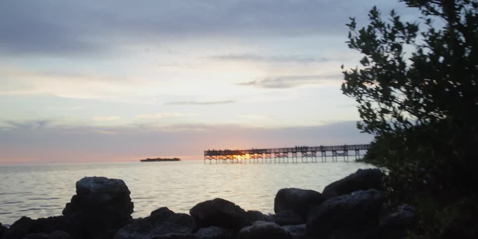 Rocks and trees sit next to the lake as a pier extends from the shoreline