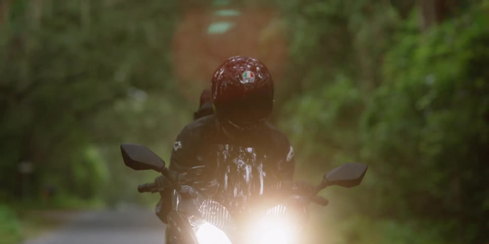 A person in a helmet rides a sleek motorcycle along a road