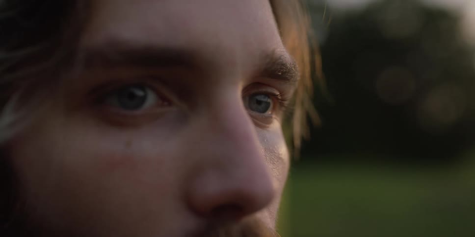 Man blinks his eyes while staring straight ahead then shifts his eyes to the right