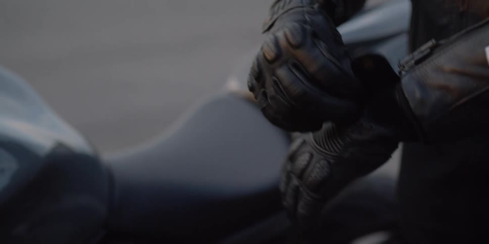 Man puts on black leather gloves before riding a motorcycle