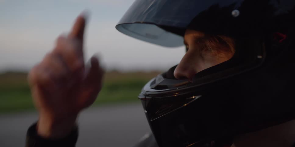 A man with a helmet with a road a grassy landscape the sky and clouds in the background